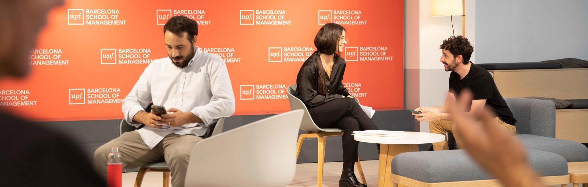Students interacting in a lounge area with UPF Barcelona School of Management branding in the background.