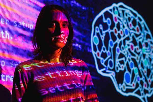 Woman surrounded by projected code and a digital brain visualization.