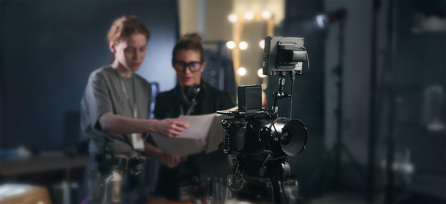 Film production professionals reviewing a script behind a professional video camera