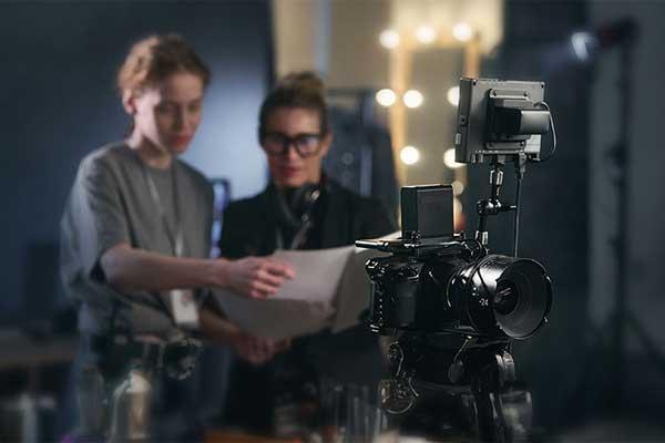 Film production professionals reviewing a script behind a professional video camera