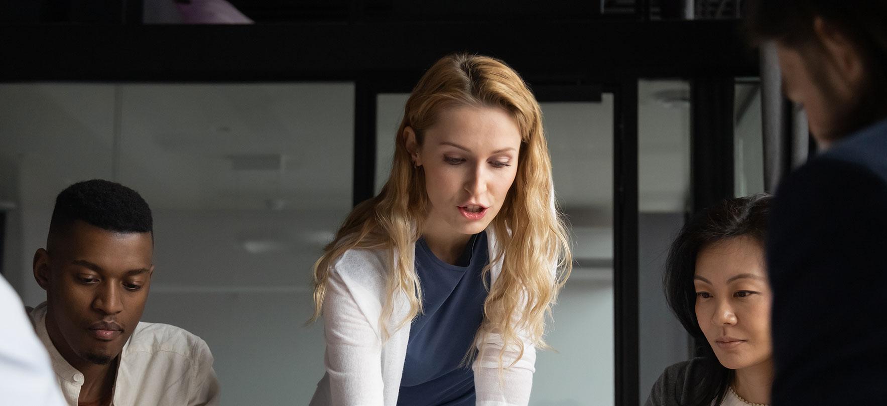 Diverse group of professionals collaborating around a table in a modern office setting.