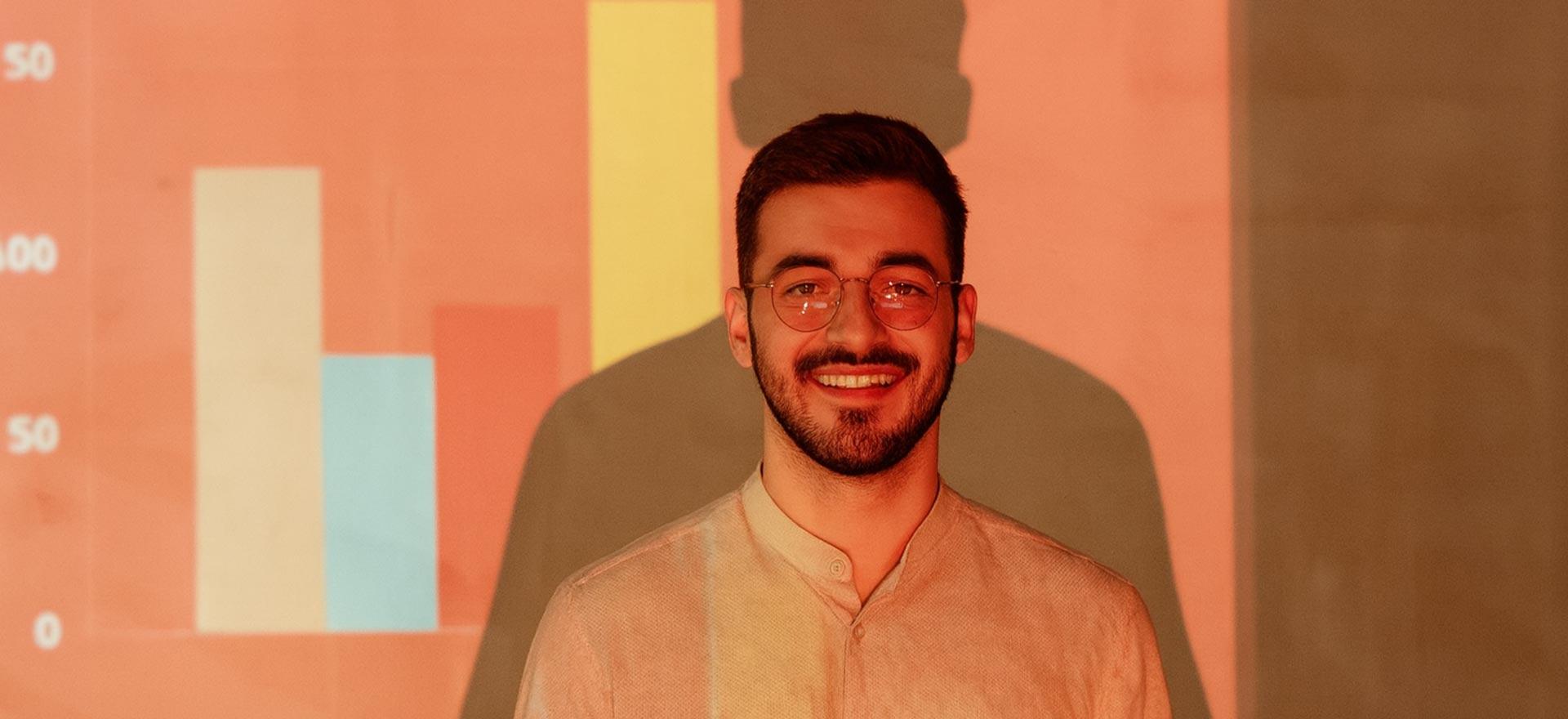 Smiling man standing in front of a projected bar chart during a presentation